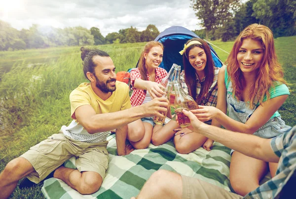 Amigos felizes com tenda e bebidas no parque de campismo — Fotografia de Stock