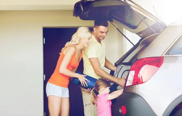 Glückliche Familie packt Sachen zum Auto auf dem Heimparkplatz — Stockfoto