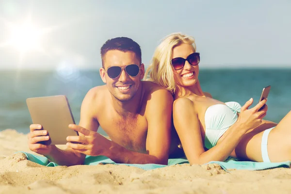 Szczęśliwa para z tabliczka pc opalając się na plaży — Zdjęcie stockowe