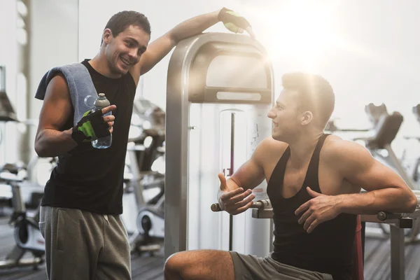 Hombres sonrientes haciendo ejercicio en la máquina de gimnasio — Foto de Stock