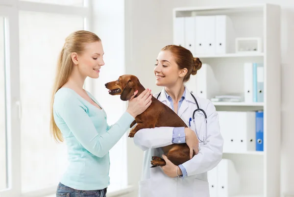 Mulher feliz com cão e médico na clínica veterinária — Fotografia de Stock