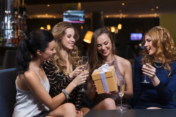 Glückliche Frauen mit Champagner und Geschenk im Nachtclub — Stockfoto