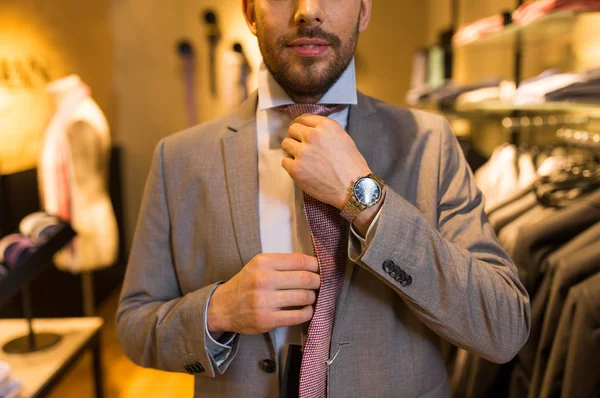 Close up of man tying tie at clothing store — Stock Photo, Image