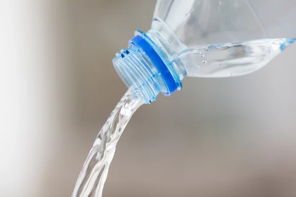 Primo piano dell'acqua versata dalla bottiglia di plastica — Foto Stock