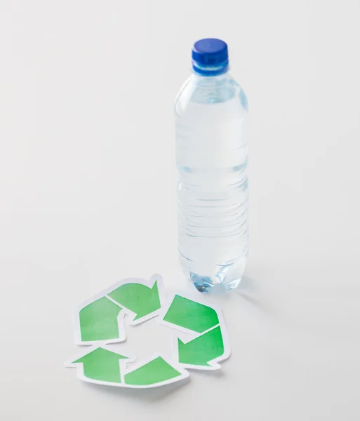 Close up of plastic bottle and recycling symbol — Stock Photo, Image