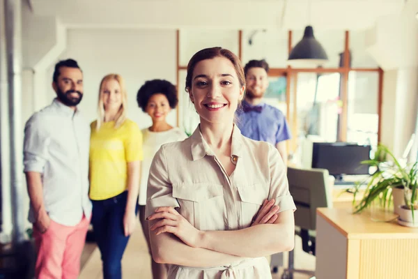 Happy young woman over creative team in office — Stock Photo, Image