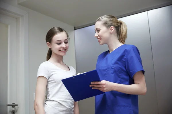 Enfermera sonriente con portapapeles y chica en el hospital — Foto de Stock
