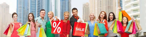 Happy people with sale sign showing thumbs up — Stock Photo, Image