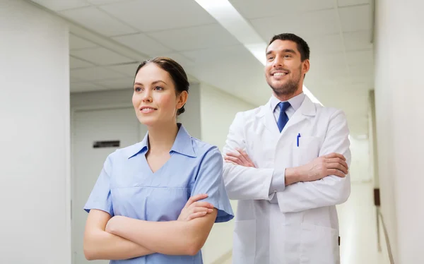 Smiling doctor in white coat and nurse at hospital — Stock Photo, Image