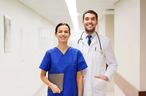 Smiling doctor in white coat and nurse at hospital — Stock Photo, Image