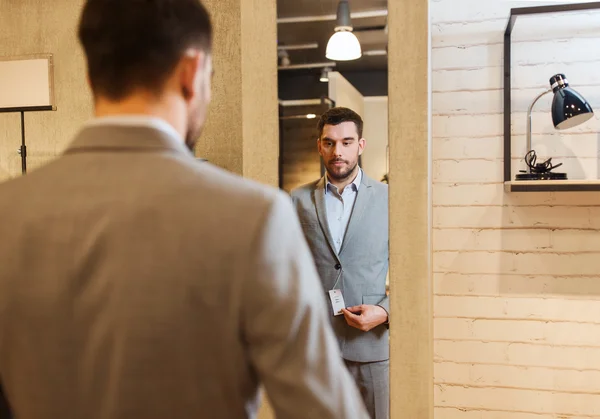 Mann probiert Anzug am Spiegel in Bekleidungsgeschäft an — Stockfoto