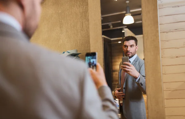 Muž v obleku s zrcadlo selfie v obchodě s oděvy — Stock fotografie