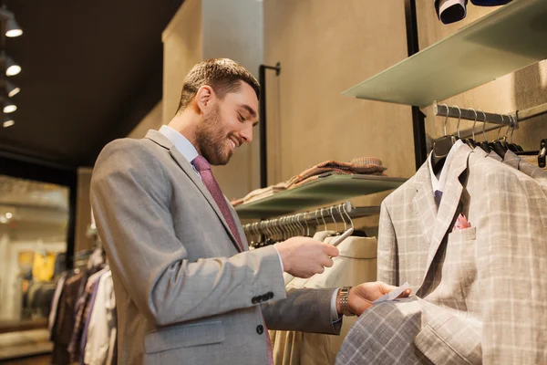 Hombre de traje con teléfono inteligente en la tienda de ropa — Foto de Stock