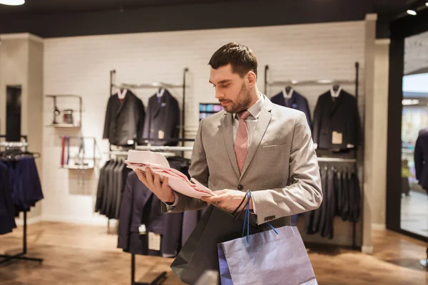 Homem com sacos de compras e camisa na loja de roupas — Fotografia de Stock