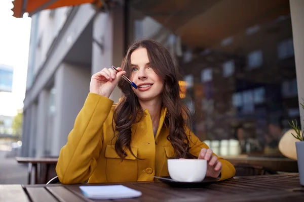 Mujer feliz con cuaderno de beber cacao en la cafetería —  Fotos de Stock