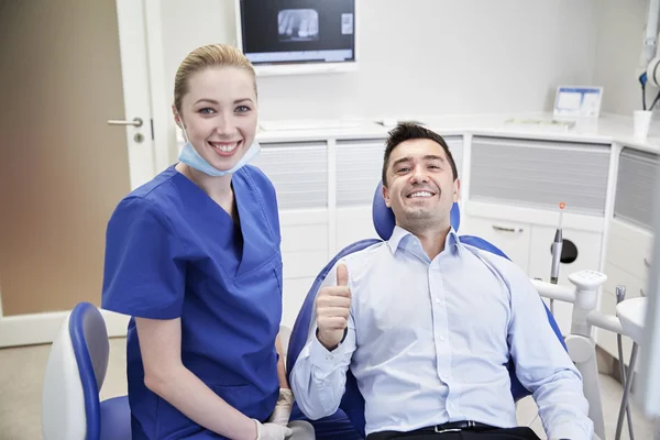 Dentista feliz do sexo feminino com paciente homem na clínica — Fotografia de Stock