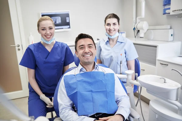 Dentistas mujeres felices con el hombre paciente en la clínica —  Fotos de Stock