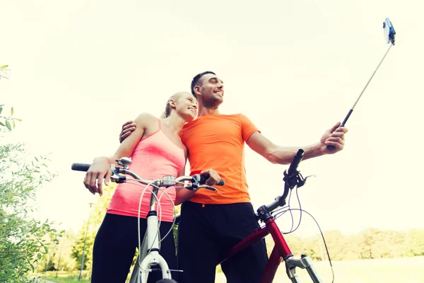 Пара з велосипедом і смартфоном selfie stick — стокове фото