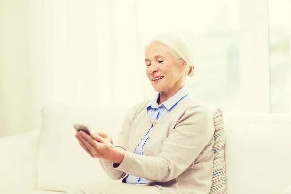 Senior woman with smartphone texting at home — Stock Photo, Image