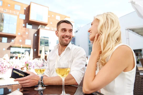 Happy couple with wallet paying bill at restaurant — Stock Photo, Image