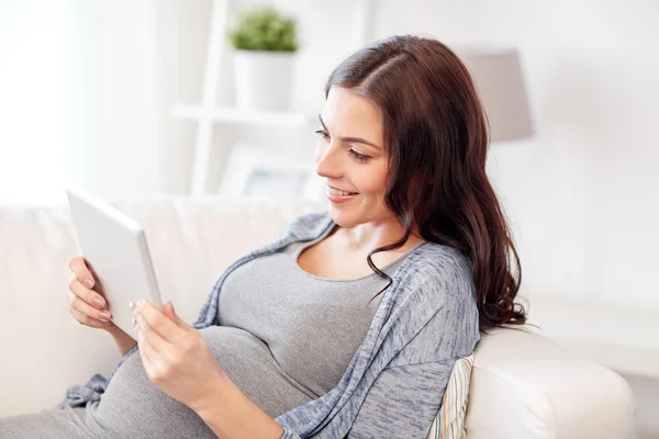 Щаслива вагітна жінка з планшетним ПК вдома — стокове фото