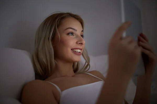 Mujer joven con tableta pc en la cama en el dormitorio en casa — Foto de Stock