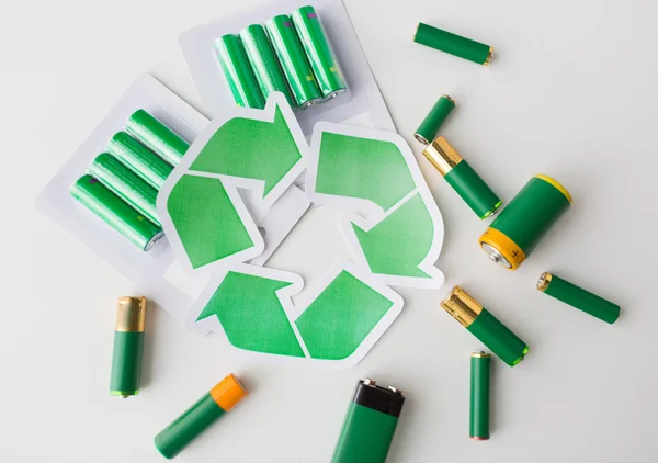 Close up of batteries and green recycling symbol — Stock Photo, Image