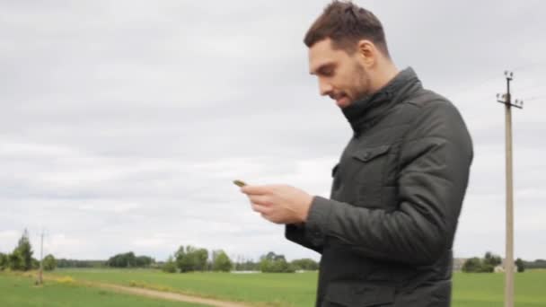 Человек со смартфоном идет по сельской дороге — стоковое видео