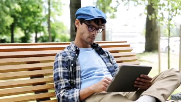 Человек с планшетным компьютером, сидящий на городской уличной скамейке — стоковое видео