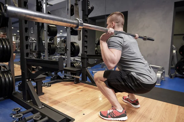 Ung man böjning muskler med bar i gymmet — Stockfoto