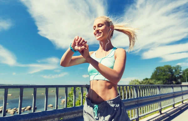 Femme heureuse avec montre de fréquence cardiaque et écouteurs — Photo