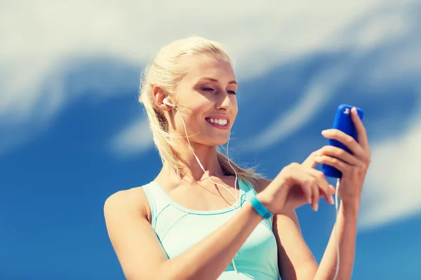 Mujer feliz con teléfono inteligente y auriculares al aire libre —  Fotos de Stock