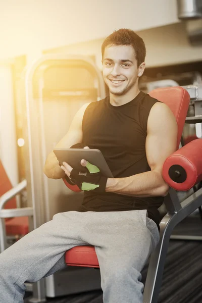 Leende ung man med tablet pc-dator i gym — Stockfoto