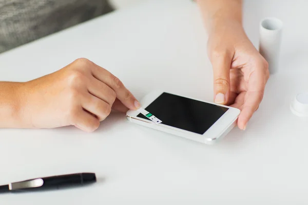 Primer plano de la mujer con teléfono inteligente haciendo análisis de sangre — Foto de Stock