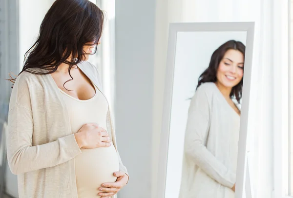 Gros plan de la femme enceinte qui cherche à miroir — Photo