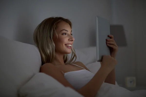 Mujer joven con tableta pc en la cama en el dormitorio en casa —  Fotos de Stock