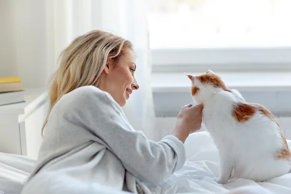 Счастливая молодая женщина с котом в постели дома — стоковое фото