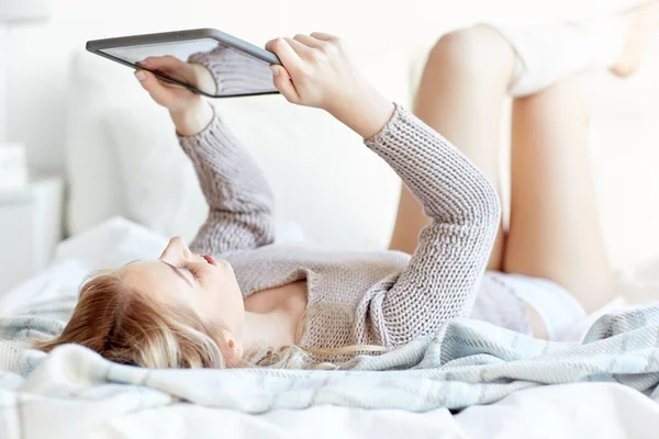 Glückliche junge Frau mit Tablet-PC zu Hause im Bett — Stockfoto