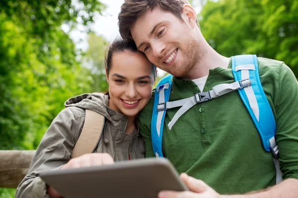 Feliz pareja con mochilas y tableta PC al aire libre — Foto de Stock