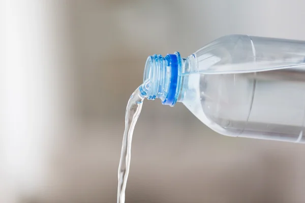 Primo piano dell'acqua versata dalla bottiglia di plastica — Foto Stock