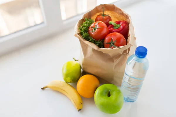 Корзина с овощной пищей и водой на кухне — стоковое фото