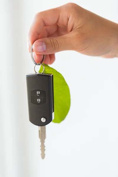 Detailní záběr rukou drží klíče od auta s zelený list — Stock fotografie