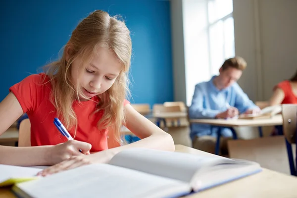 Estudante menina com livro escrevendo teste de escola — Fotografia de Stock