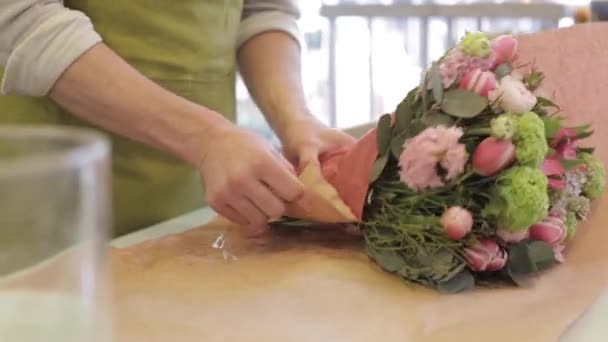 Цветочник заворачивает цветы в бумагу в цветочном магазине — стоковое видео