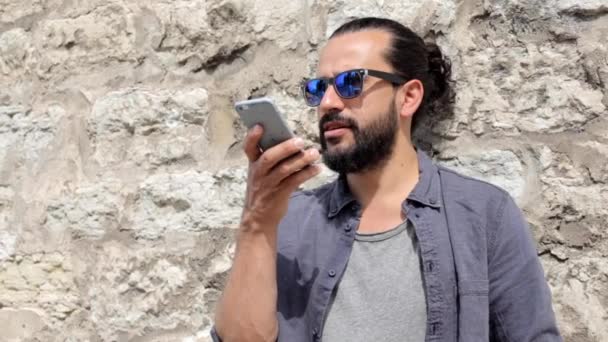 Улыбающийся мужчина со смартфоном звонит на городской улице — стоковое видео