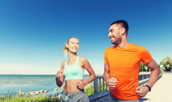 Sonriente pareja corriendo en verano junto al mar — Foto de Stock