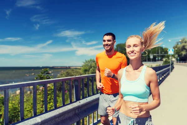 Lächelndes Paar läuft am sommerlichen Meer — Stockfoto