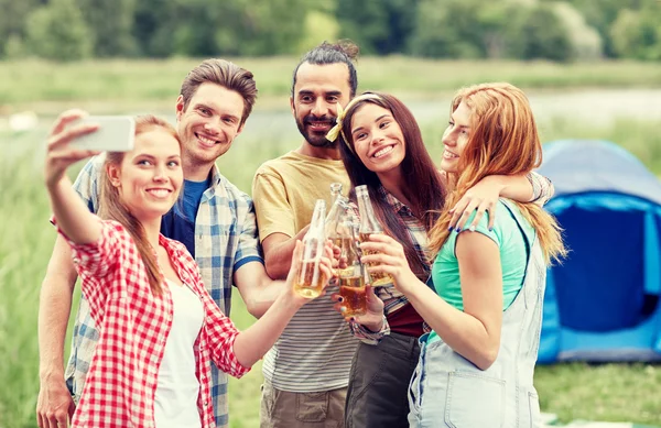 Happy friends taking selfie by smartphone at camp — Stock Photo, Image