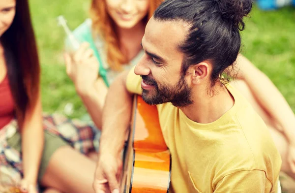 Lycklig man med vänner spelar gitarr på camping — Stockfoto
