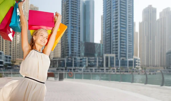 Femme heureuse avec des sacs à provisions sur la ville de Dubai — Photo